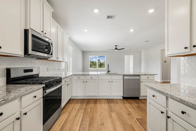 kitchen with sink, light hardwood / wood-style flooring, white cabinetry, stainless steel appliances, and light stone countertops