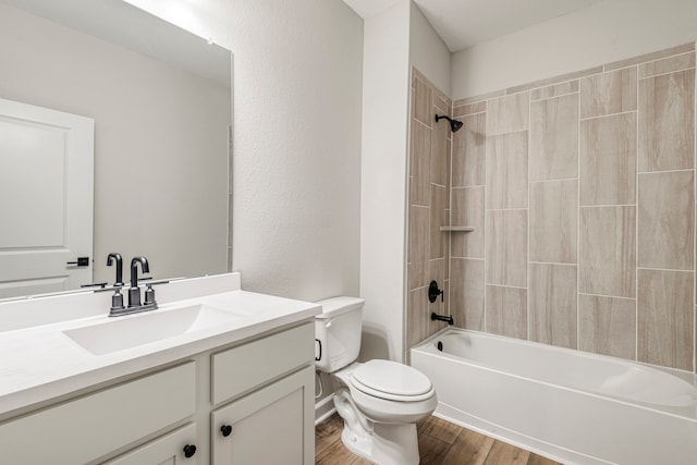 full bathroom featuring tiled shower / bath, vanity, toilet, and hardwood / wood-style floors