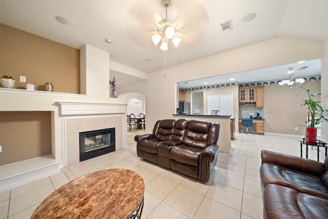 tiled living room featuring a tiled fireplace, vaulted ceiling, and ceiling fan