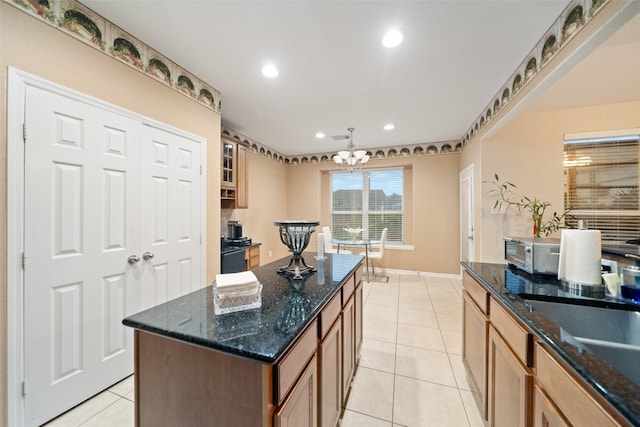 kitchen with a chandelier, a center island, dark stone countertops, light tile patterned floors, and pendant lighting