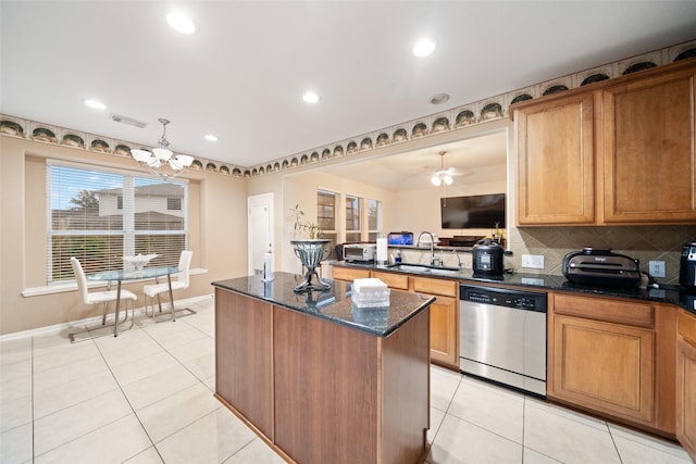 kitchen with sink, dark stone counters, a center island, stainless steel dishwasher, and light tile patterned floors