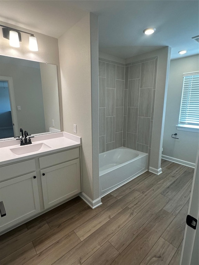 bathroom with hardwood / wood-style flooring, vanity, and tiled shower / bath combo