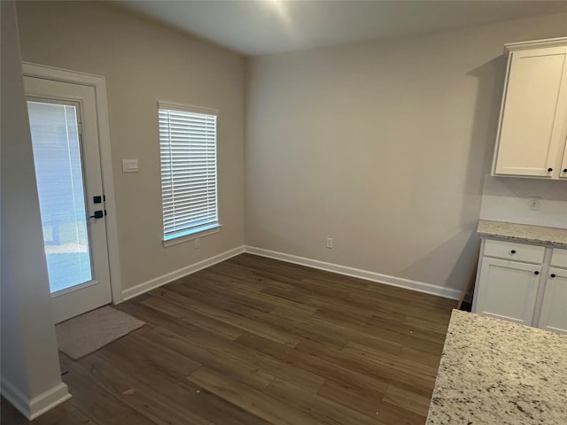 unfurnished dining area with dark wood-type flooring