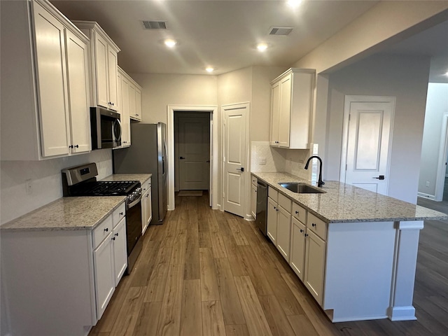 kitchen featuring appliances with stainless steel finishes, sink, white cabinets, and light stone counters