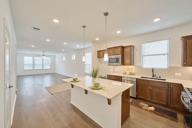 kitchen featuring stainless steel appliances, tasteful backsplash, visible vents, a sink, and wood finished floors