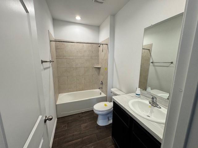 full bathroom featuring hardwood / wood-style flooring, tiled shower / bath, vanity, and toilet