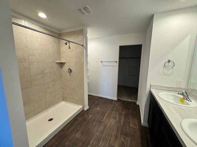 bathroom with wood-type flooring, a tile shower, and vanity