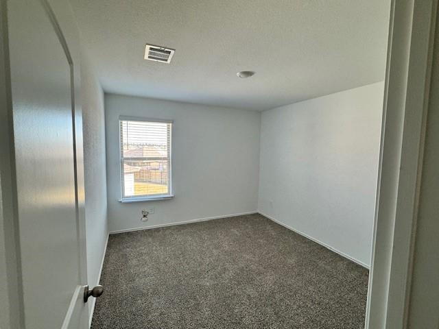 carpeted empty room featuring a textured ceiling