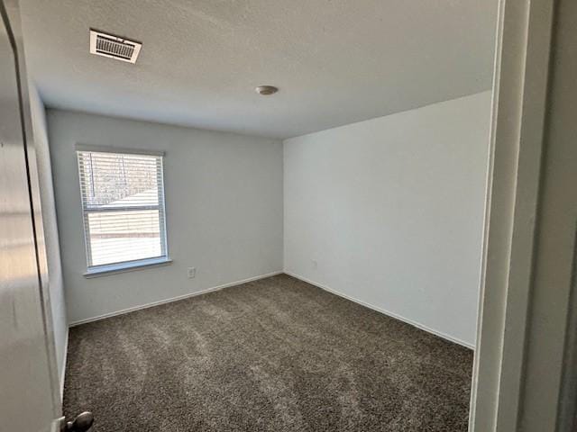 empty room featuring dark carpet and a textured ceiling