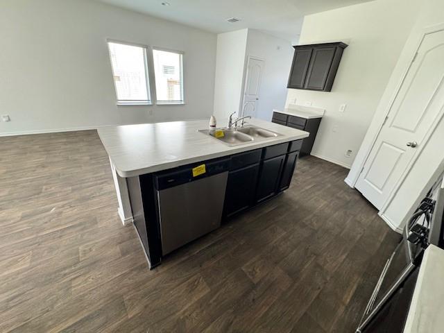 kitchen featuring sink, stainless steel dishwasher, a kitchen island with sink, and dark wood-type flooring