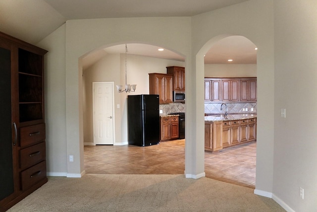 kitchen with vaulted ceiling, decorative backsplash, light colored carpet, black appliances, and an inviting chandelier