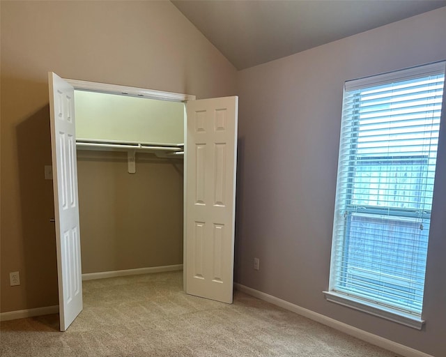 unfurnished bedroom with vaulted ceiling, light colored carpet, and a closet