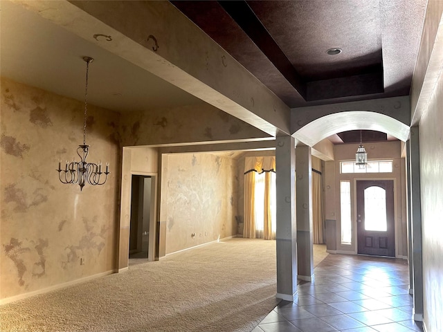 carpeted foyer entrance with an inviting chandelier, a raised ceiling, and a high ceiling