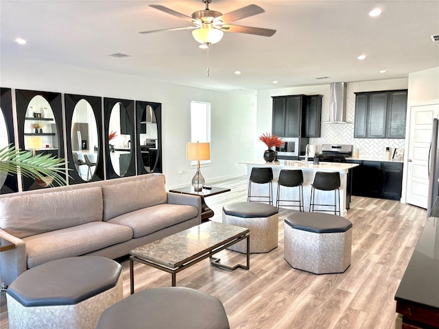 living room featuring ceiling fan, sink, and light hardwood / wood-style floors