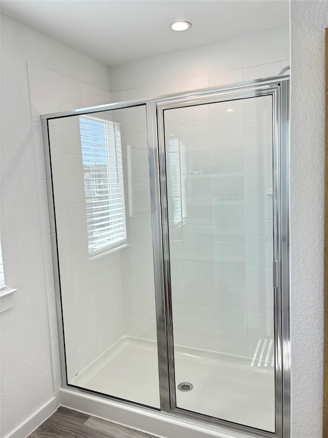 bathroom with wood-type flooring and a shower with shower door