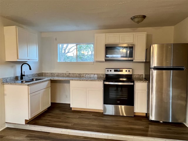 kitchen with sink, light stone counters, appliances with stainless steel finishes, dark hardwood / wood-style floors, and white cabinets