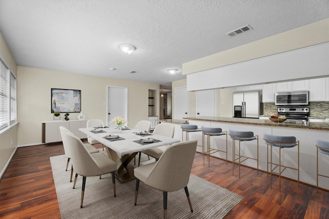 dining area with dark wood-type flooring and a textured ceiling