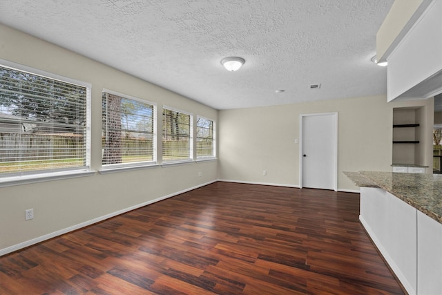 unfurnished living room with dark hardwood / wood-style flooring and a textured ceiling