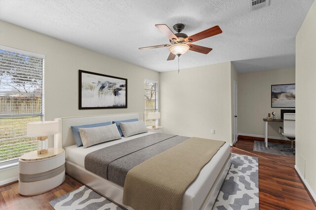 bedroom with dark wood-type flooring, ceiling fan, and a textured ceiling