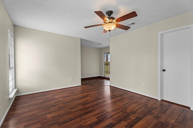 empty room with dark wood-type flooring, ceiling fan, and a textured ceiling