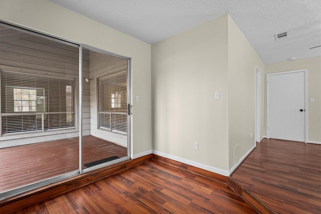 spare room featuring dark wood-type flooring and a textured ceiling