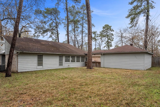 back of house with central air condition unit and a lawn