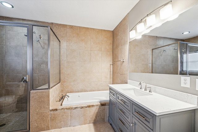 bathroom featuring vanity, independent shower and bath, and tile walls