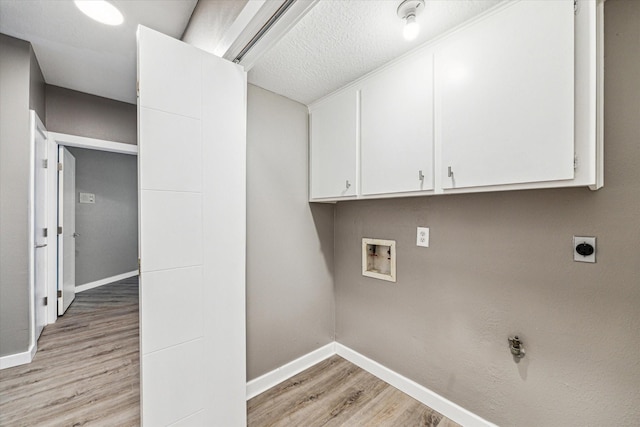 laundry room with electric dryer hookup, washer hookup, light hardwood / wood-style floors, and cabinets
