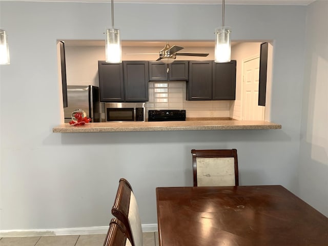 kitchen featuring stainless steel appliances, pendant lighting, kitchen peninsula, and decorative backsplash