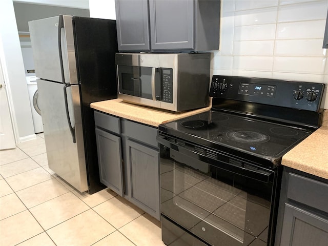 kitchen with gray cabinetry, appliances with stainless steel finishes, light tile patterned floors, and backsplash