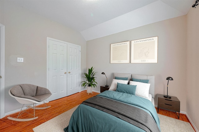 bedroom with a closet, lofted ceiling, and wood-type flooring