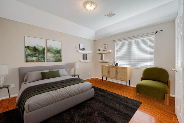 bedroom with wood-type flooring and vaulted ceiling