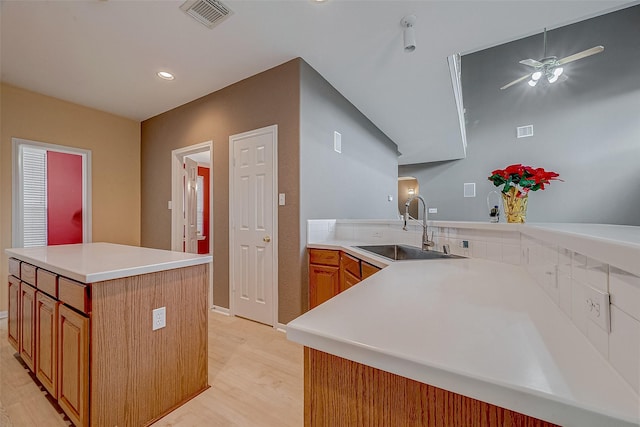 kitchen featuring sink, light hardwood / wood-style floors, a center island, and kitchen peninsula