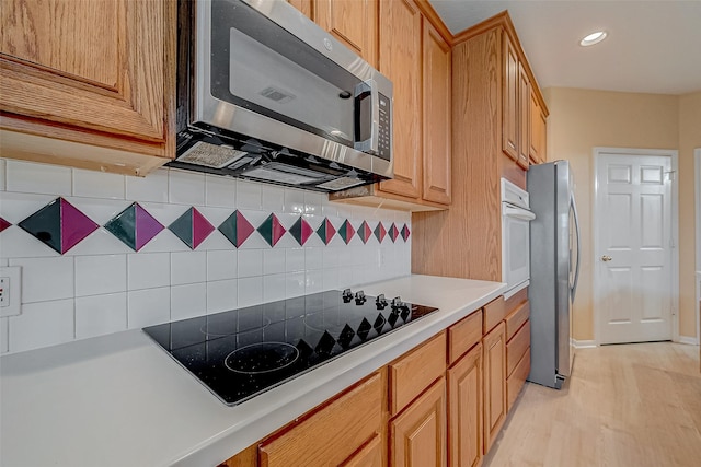 kitchen with tasteful backsplash, light hardwood / wood-style flooring, and appliances with stainless steel finishes