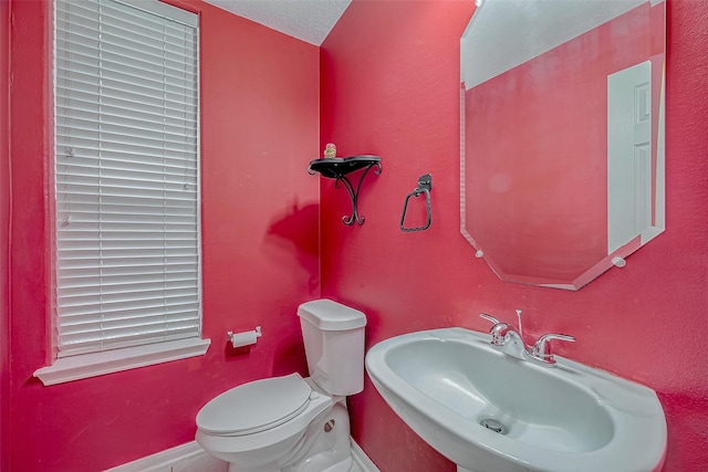 bathroom featuring toilet, sink, and a textured ceiling