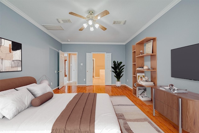 bedroom featuring crown molding, ceiling fan, light hardwood / wood-style floors, and ensuite bath