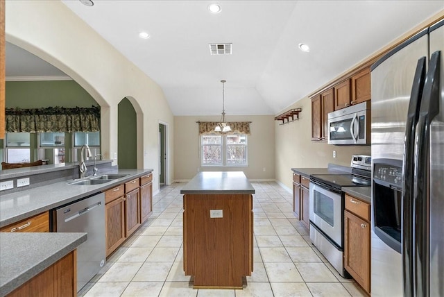 kitchen with lofted ceiling, sink, decorative light fixtures, a kitchen island, and stainless steel appliances