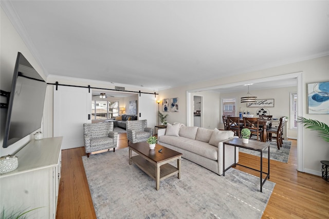 living room with ornamental molding, a barn door, and light hardwood / wood-style floors