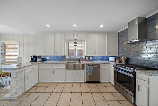 kitchen featuring wall chimney exhaust hood, sink, appliances with stainless steel finishes, kitchen peninsula, and white cabinets