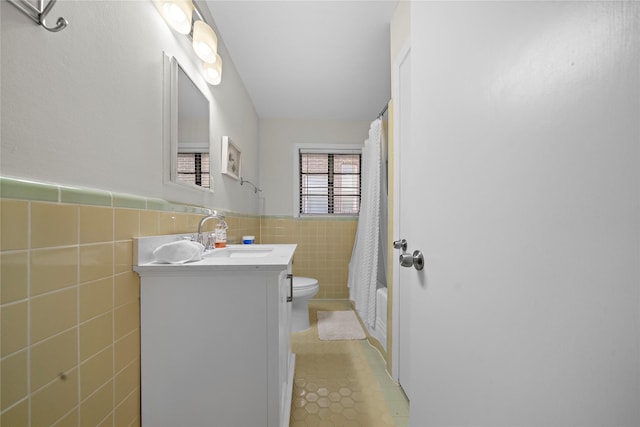 full bathroom featuring shower / tub combo with curtain, tile walls, tile patterned flooring, vanity, and toilet