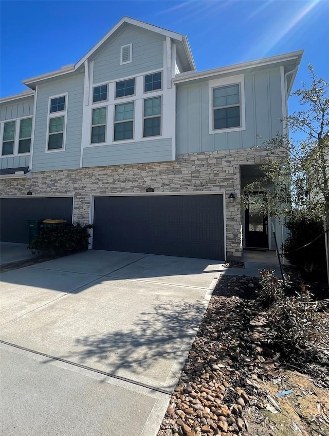 multi unit property featuring board and batten siding, stone siding, driveway, and a garage