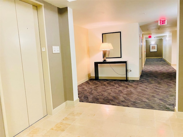 hallway with elevator and light colored carpet