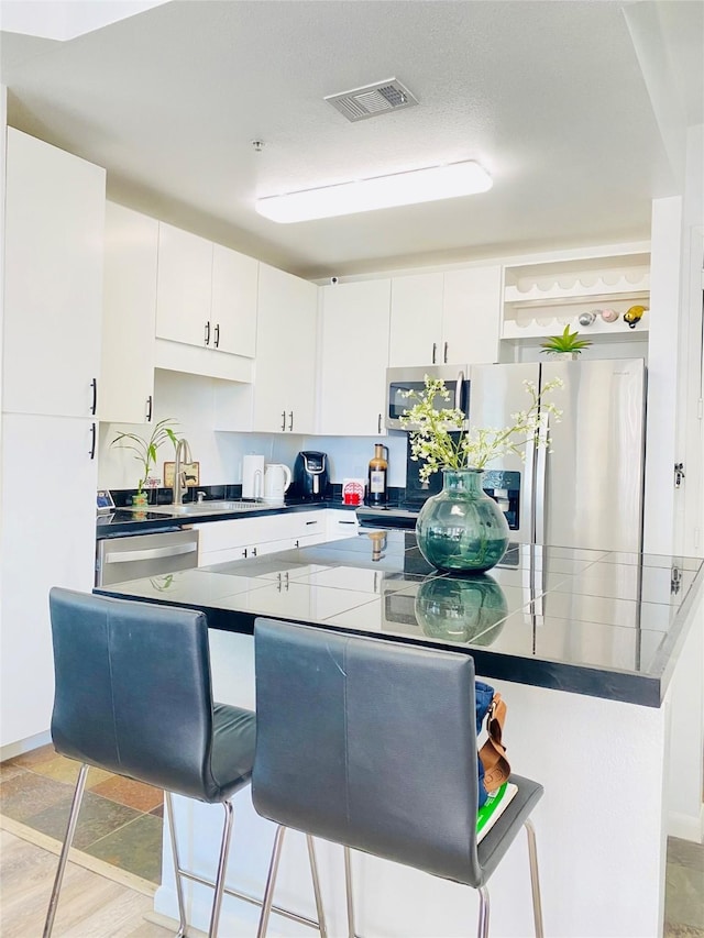 kitchen with stainless steel appliances, sink, and white cabinets