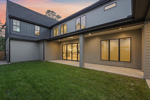 back house at dusk with a yard and a patio area