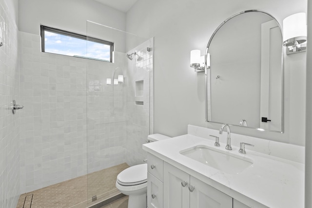 bathroom featuring vanity, a tile shower, and toilet