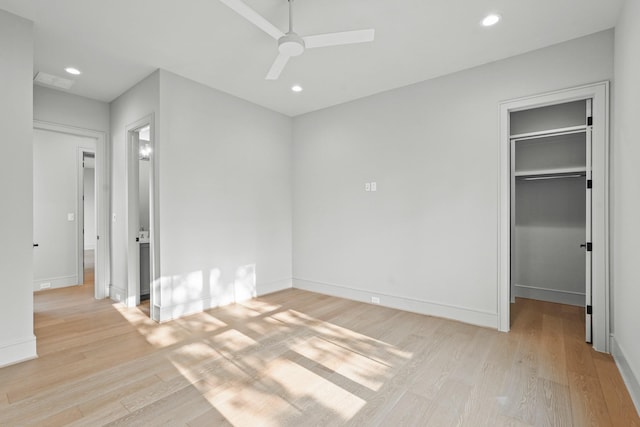 unfurnished bedroom with ceiling fan, a walk in closet, light hardwood / wood-style floors, and a closet