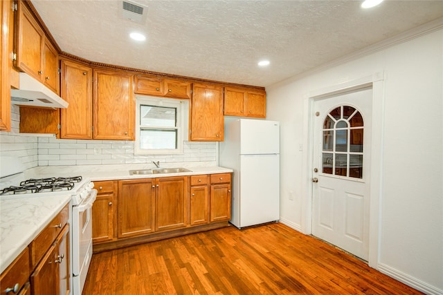 kitchen with dark hardwood / wood-style floors, sink, backsplash, white appliances, and a textured ceiling