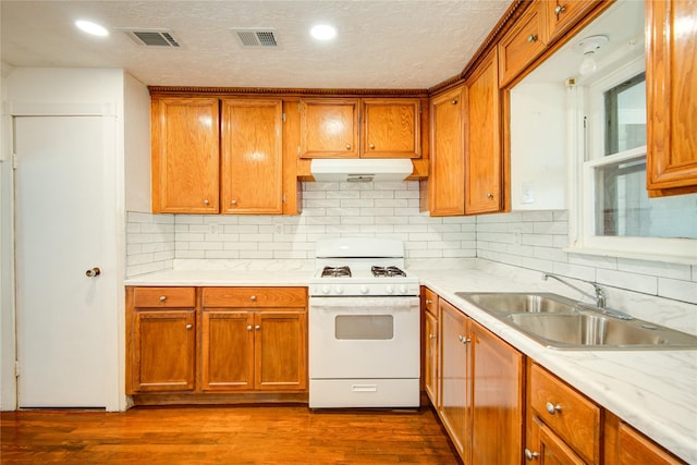 kitchen featuring sink, backsplash, hardwood / wood-style floors, and white gas stove