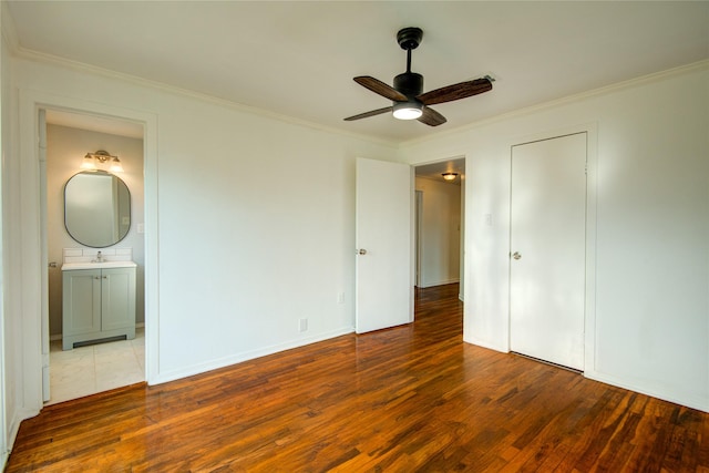 unfurnished bedroom featuring hardwood / wood-style flooring, crown molding, sink, and ensuite bathroom