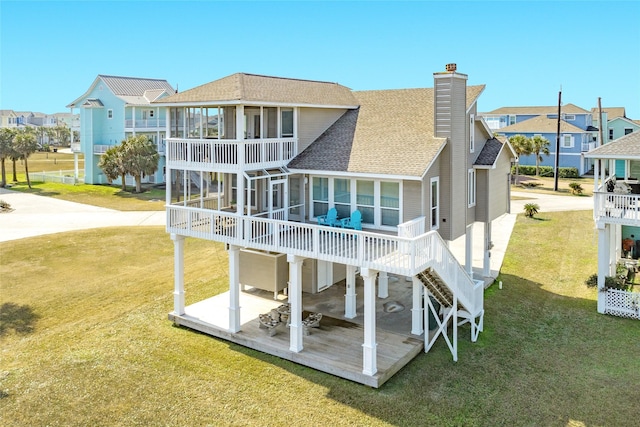 rear view of house with a lawn, a sunroom, and a patio